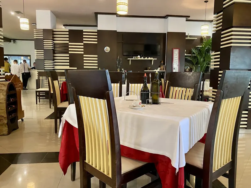 The dining room: white and red tablecloths, dark wooden chairs and striped columns