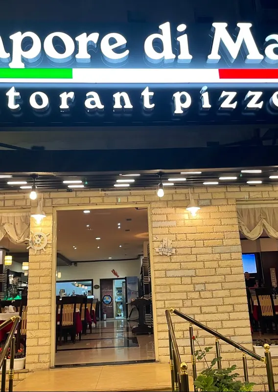 The lit Sapore di Mare sign at night above the open entrance
