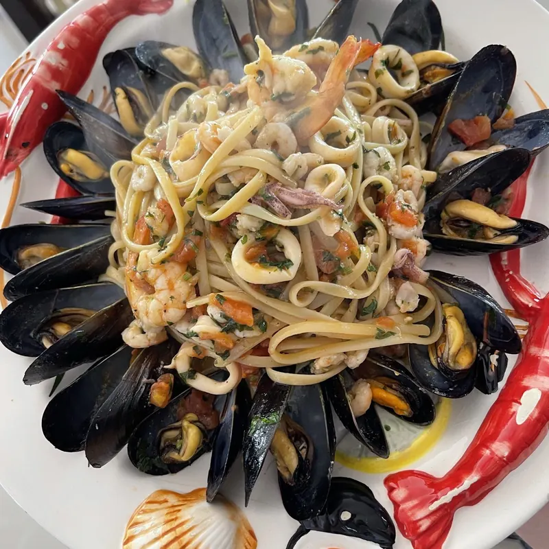 Seafood linguine with mussels, shrimp and calamari on a plate painted with shells and lobsters