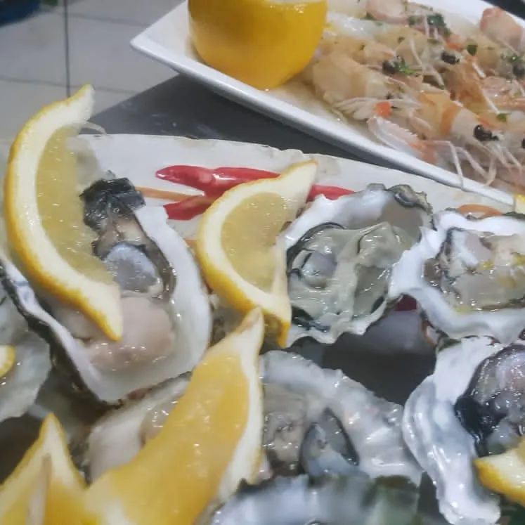 Oysters with lemon wedges next to a platter of shrimp
