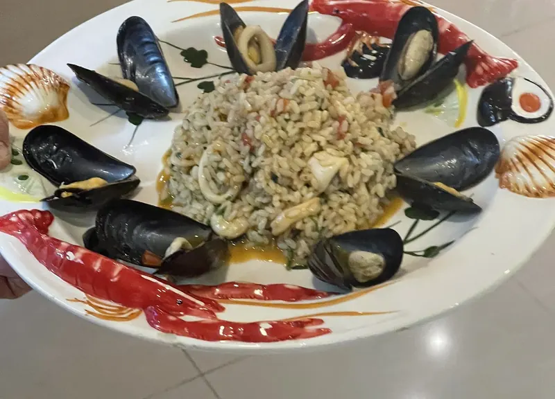 Seafood risotto ringed with mussels on a hand-painted plate