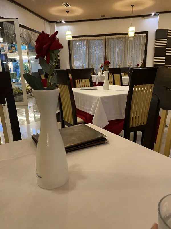 A laid table with a single red rose in a white vase